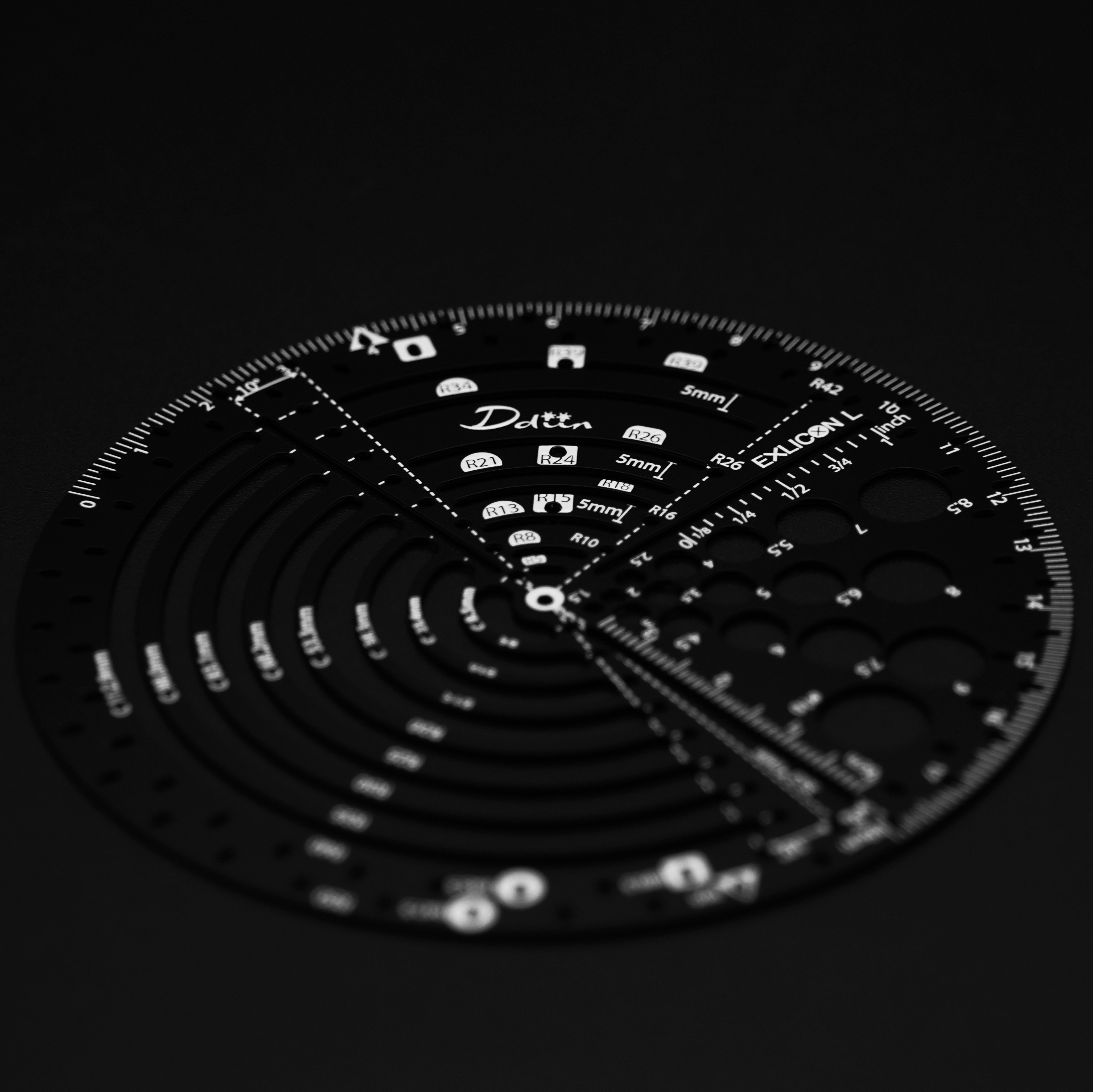 Black circular ruler with measurement markings for perfect golden ratio on a black background