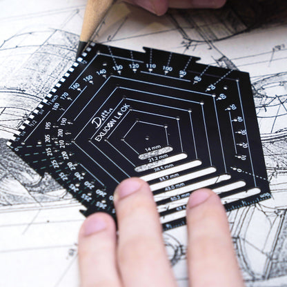 Person holding a black pentagon geometric tool over architectural drawings