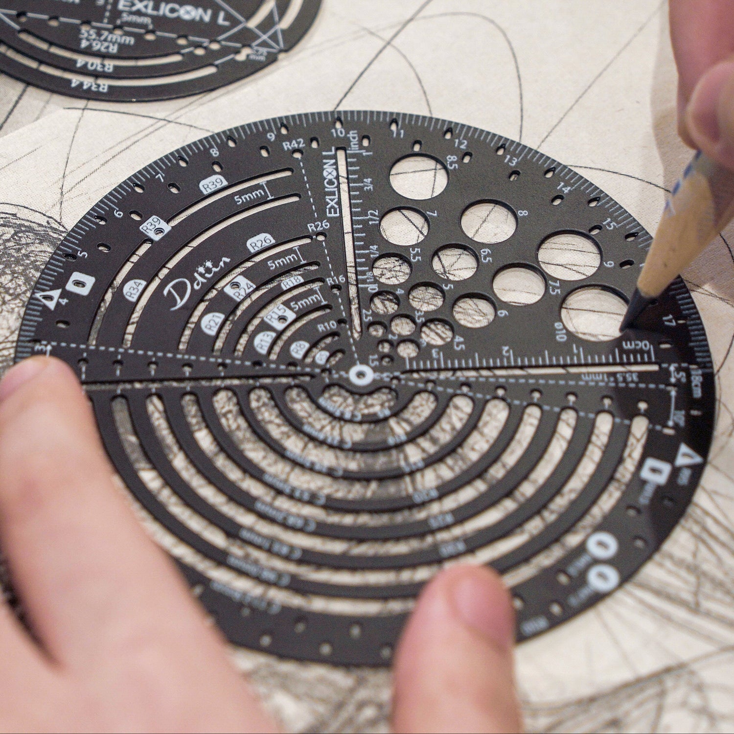 Person using a black circular ruler with measurement markings for art and geometry
