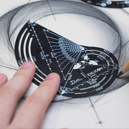 Person drawing intricate geometric designs on paper with a black golden ratio compass with measurement markings