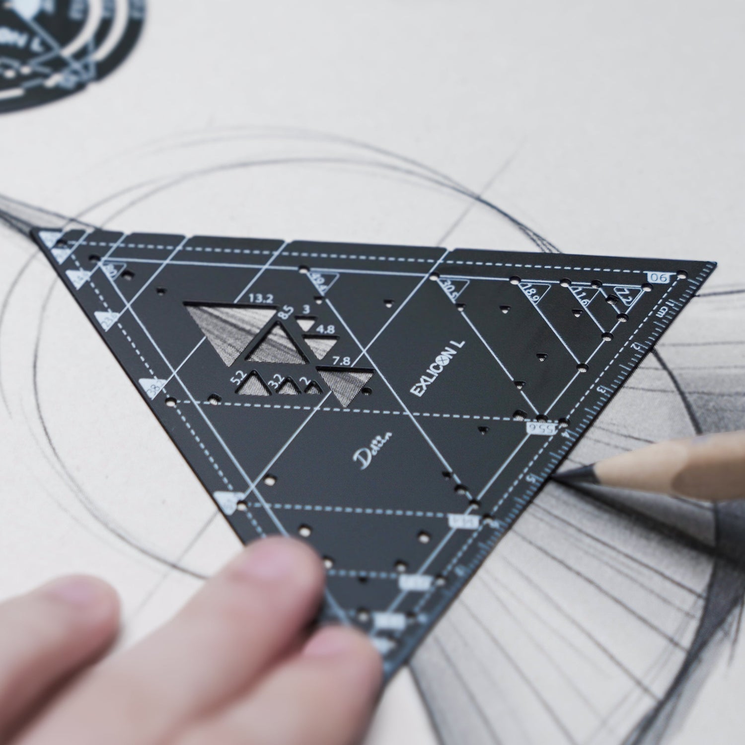 Person using a protractor on architectural designs with a black triangle compass